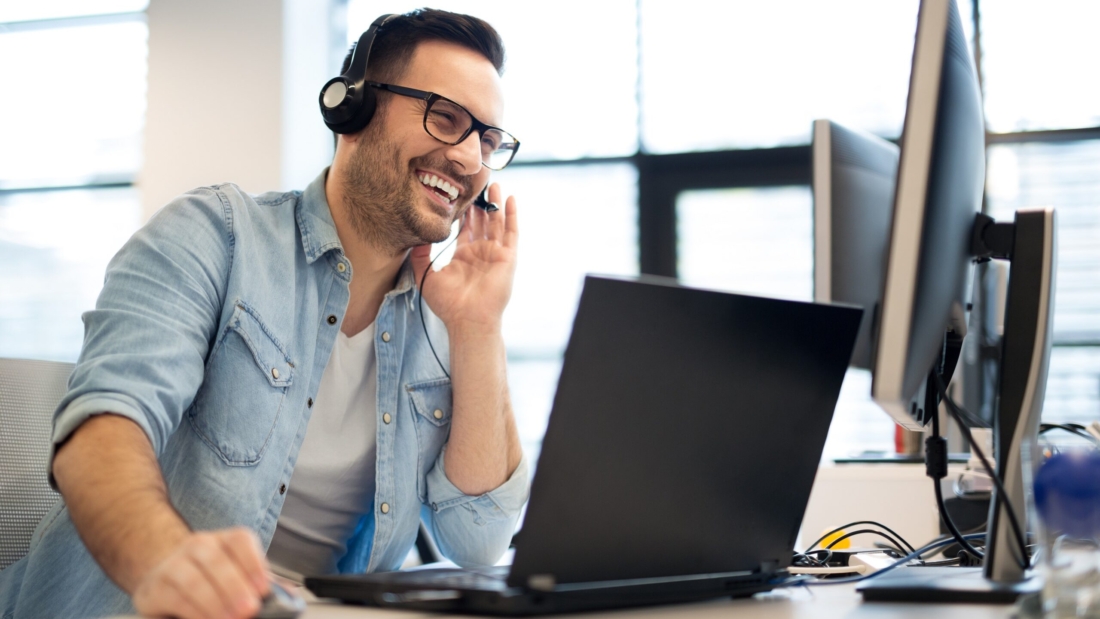 Young smiling male call center operator doing his job with a hea