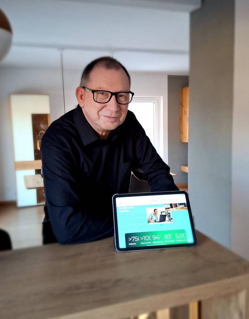 Favorent Bayern: Mann zeigt Tablet mit Ferienhaus-Verwaltungssoftware. Maximaler Ertrag, minimaler Aufwand für Ihr Ferienhaus.