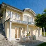 Helles Ferienhaus mit Terrasse und Gartenmöbeln unter blauem Himmel. Favorent bietet professionelle Ferienhausverwaltung.