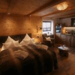 Holzvertäfelter Wohnbereich mit Bett und Küchenzeile, geeignet für die Vermietung als Ferienimmobilie.