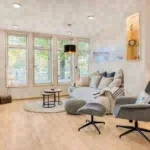 Wohnzimmer mit Sofa, Sessel und Blick aus dem Fenster, geeignet für die Ferienhausverwaltung.