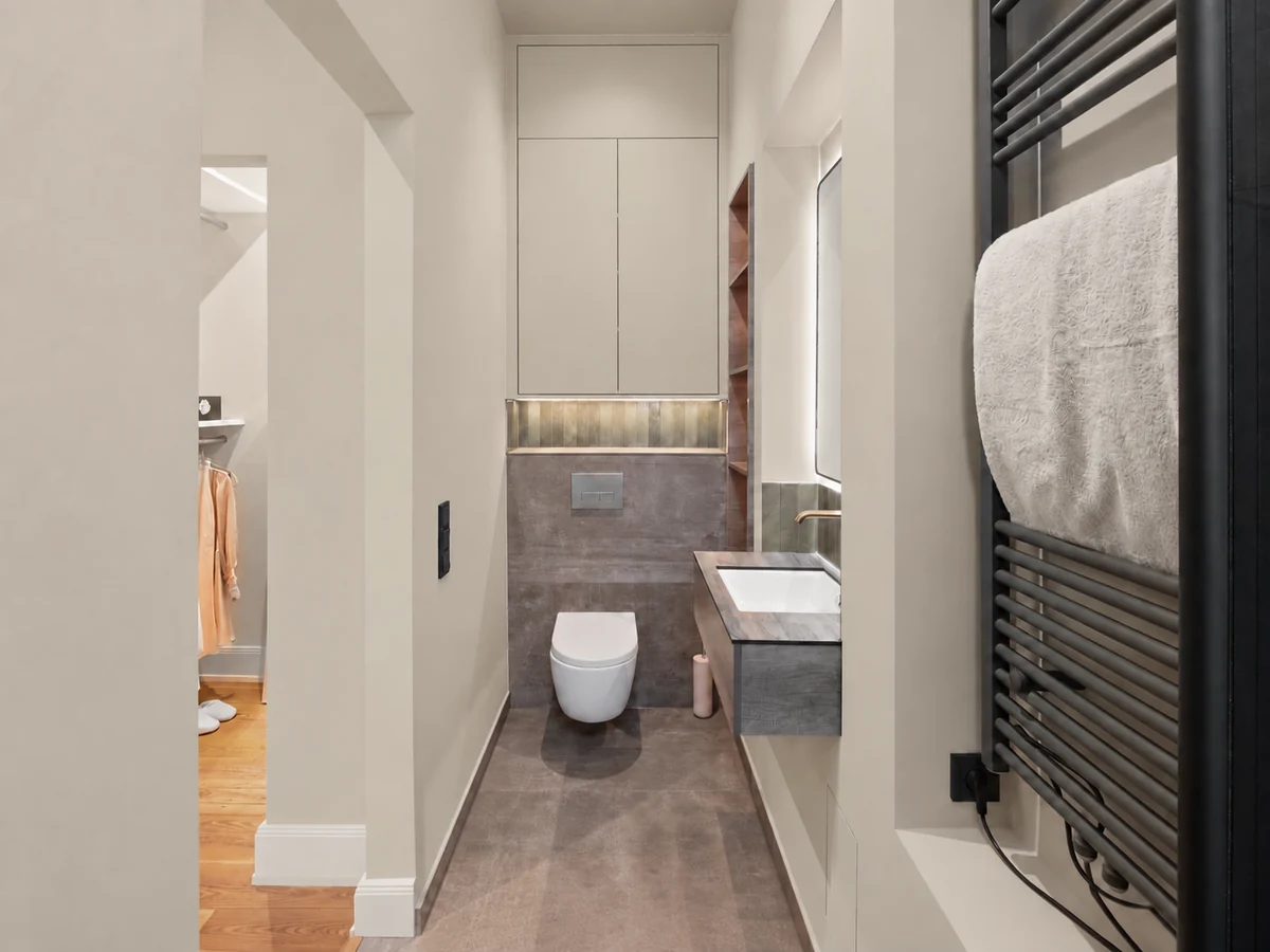 Neues kleines Bad der Suite mit Wand-WC, Waschtisch und Handtuchheizkörper
