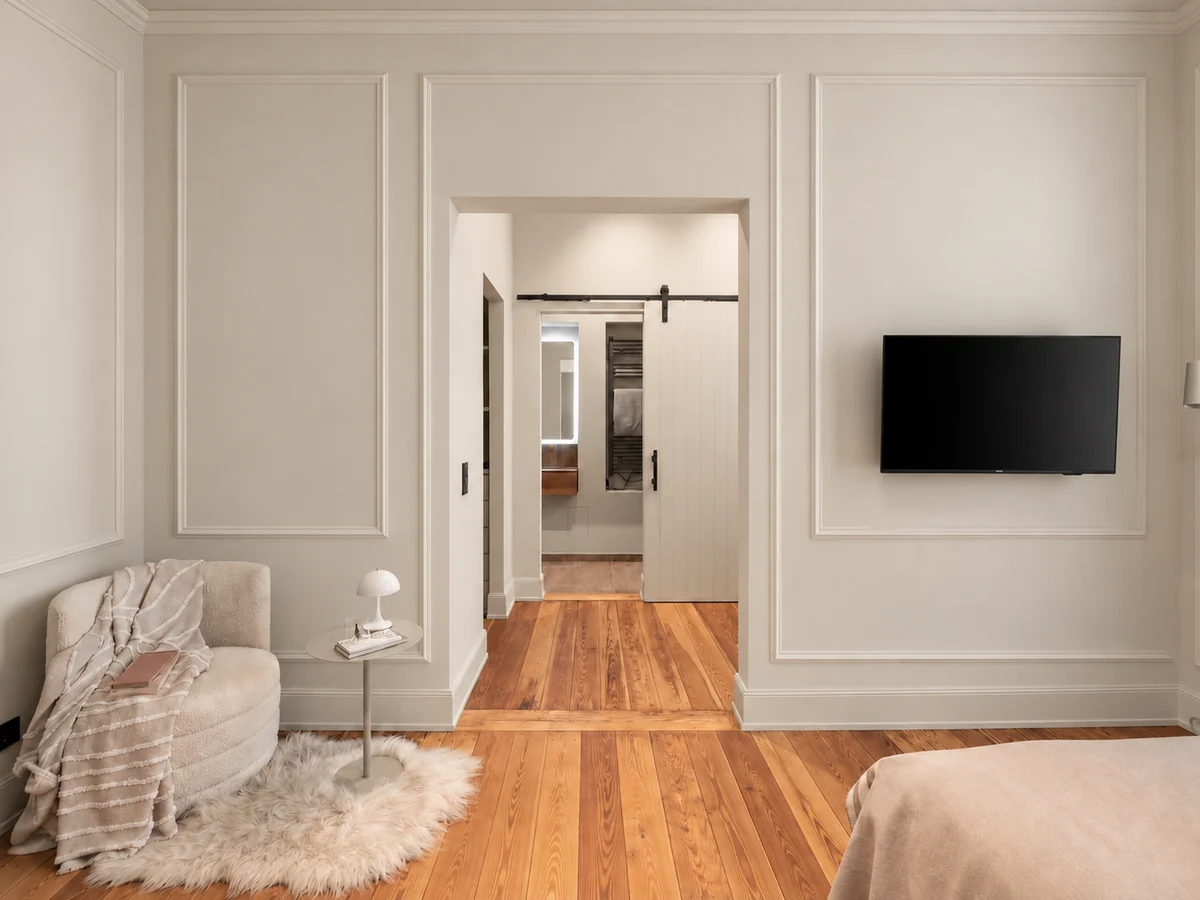 Zimmer der Suite mit Sessel, Fernseher und Schiebetür zum Bad