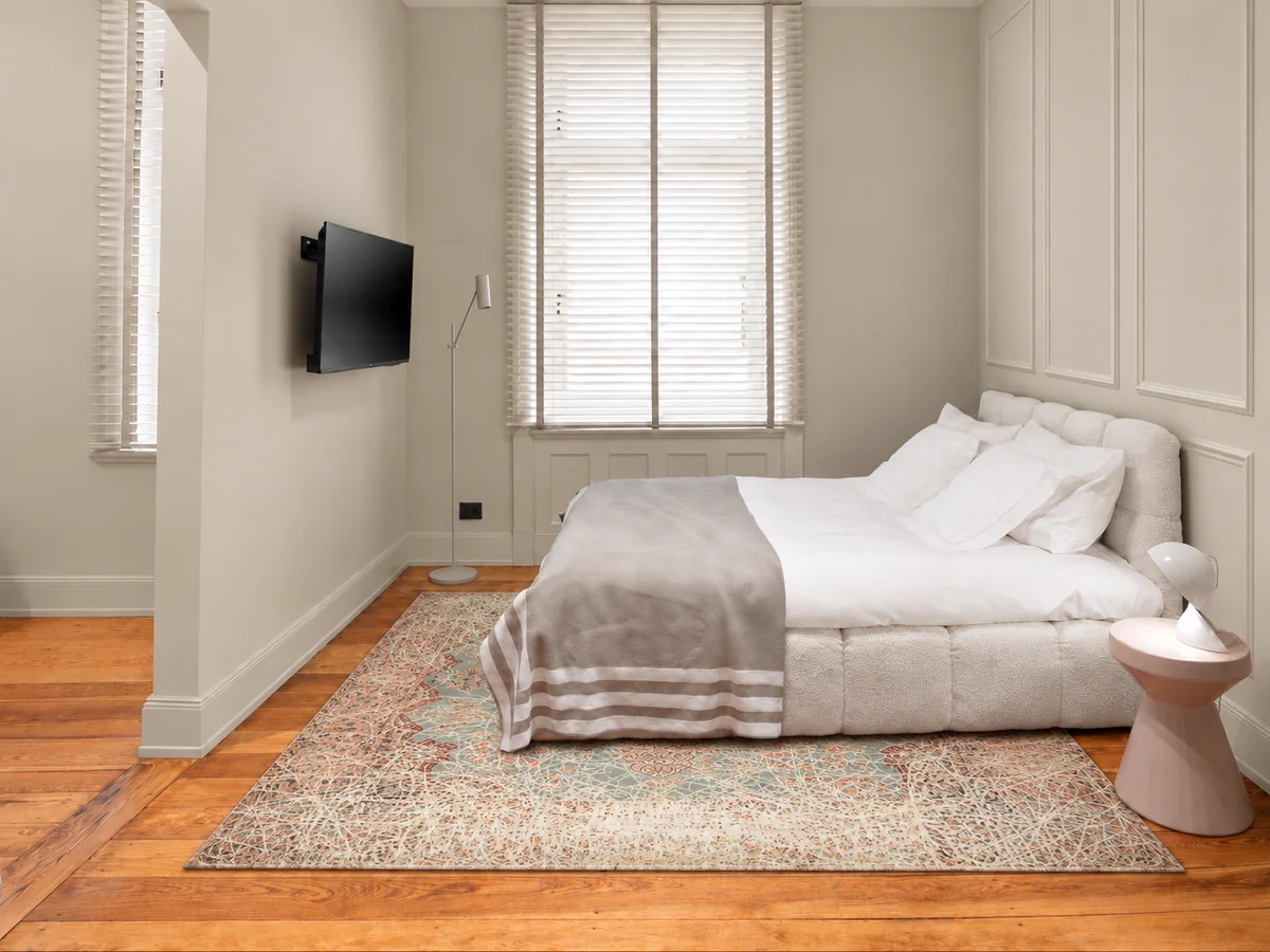 Schlafbereich der Suite mit Doppelbett, Perserteppich und heller Wandvertäfelung