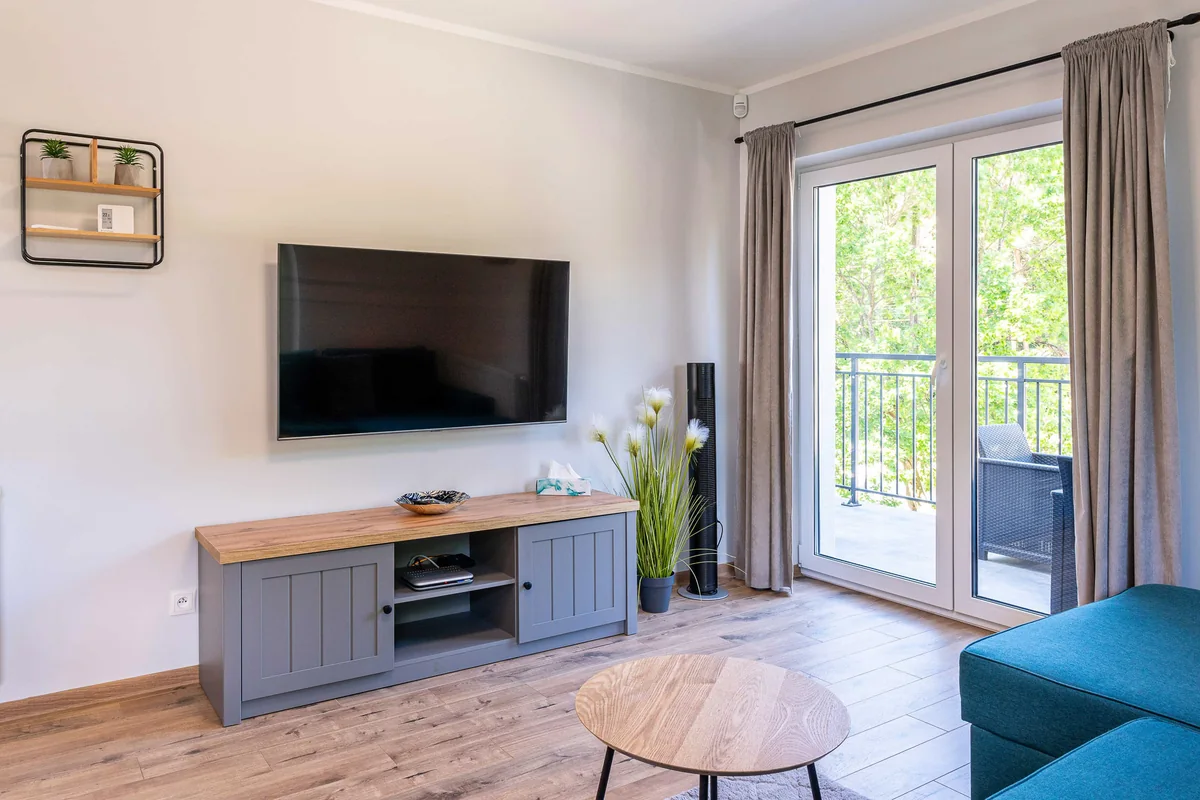 Wohnbereich mit Fernseher, Couchtisch und Balkontür