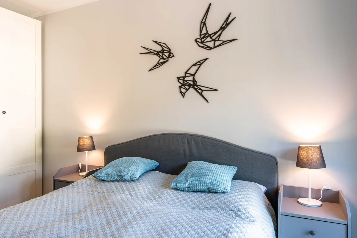Schlafzimmer mit Doppelbett, Nachttischlampen und Vogelmotiven an der Wand
