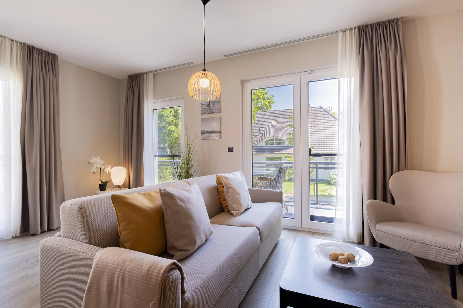 Heller Wohnbereich mit Sofa, Sessel und Balkontür in einer Ferienwohnung, fotografiert von grund & form.