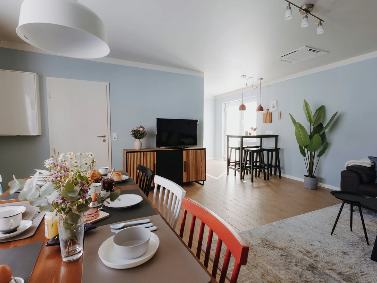 Essbereich im Haus Juist nachher, mit gedecktem Tisch, rotem und weißem Stuhl und Blick in den Wohnraum