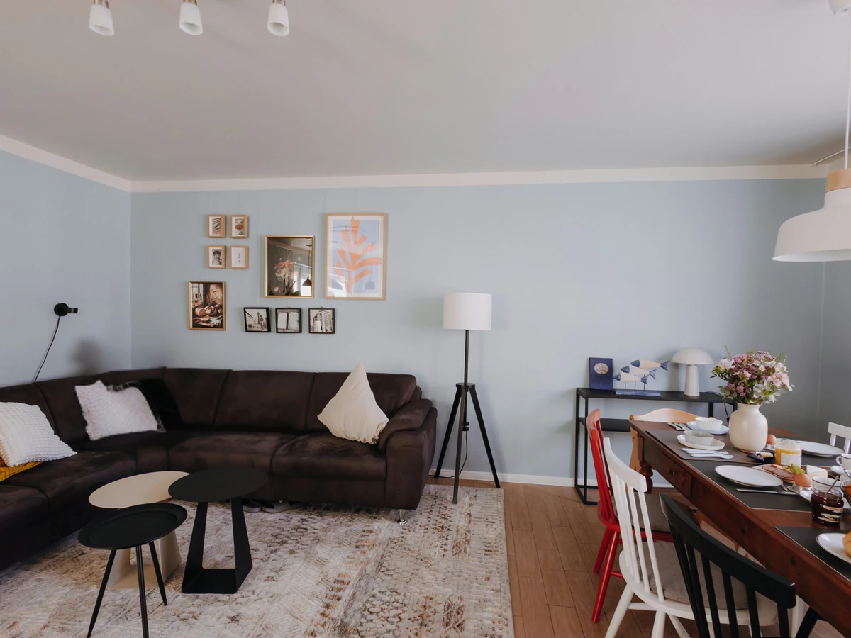 Wohnzimmer im Haus Juist nachher, mit hellblauer Wand, Bildergalerie und farbigen Stühlen