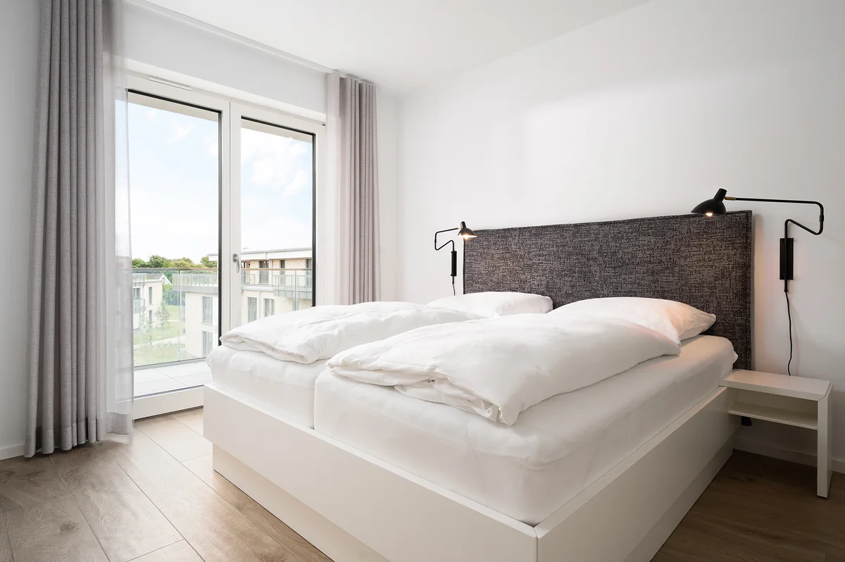 Schlafzimmer mit Polsterkopfteil, Leseleuchten und bodentiefem Fenster