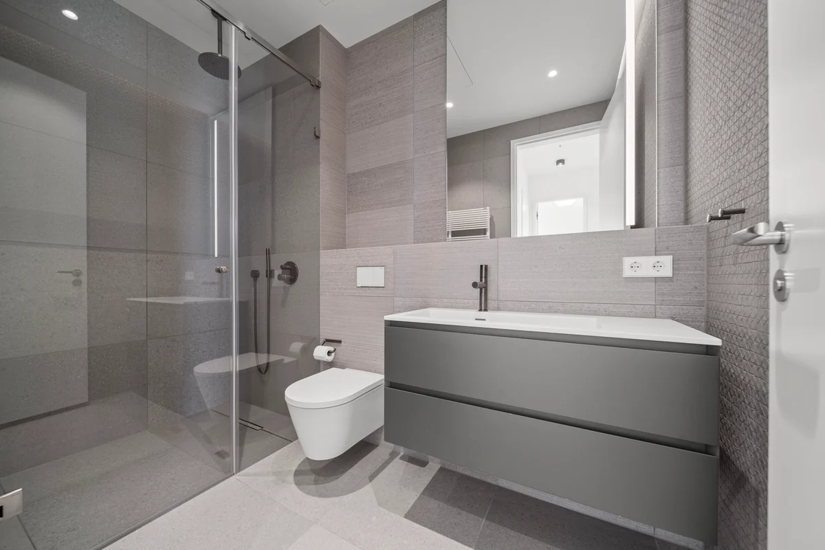 Bad mit Glasdusche, grauem Waschtisch und Wand-WC