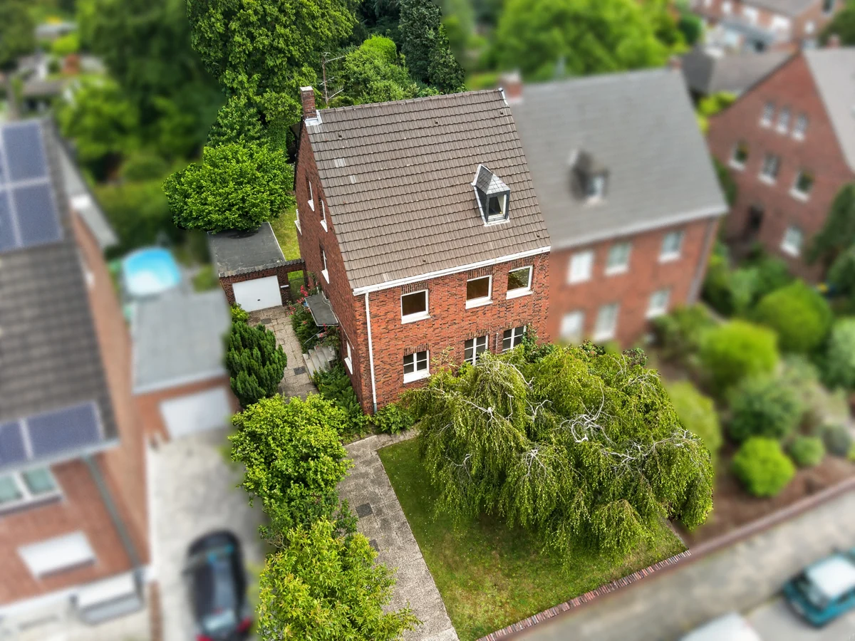 Luftaufnahme eines Backsteinhauses mit Garten in einer Wohnstraße
