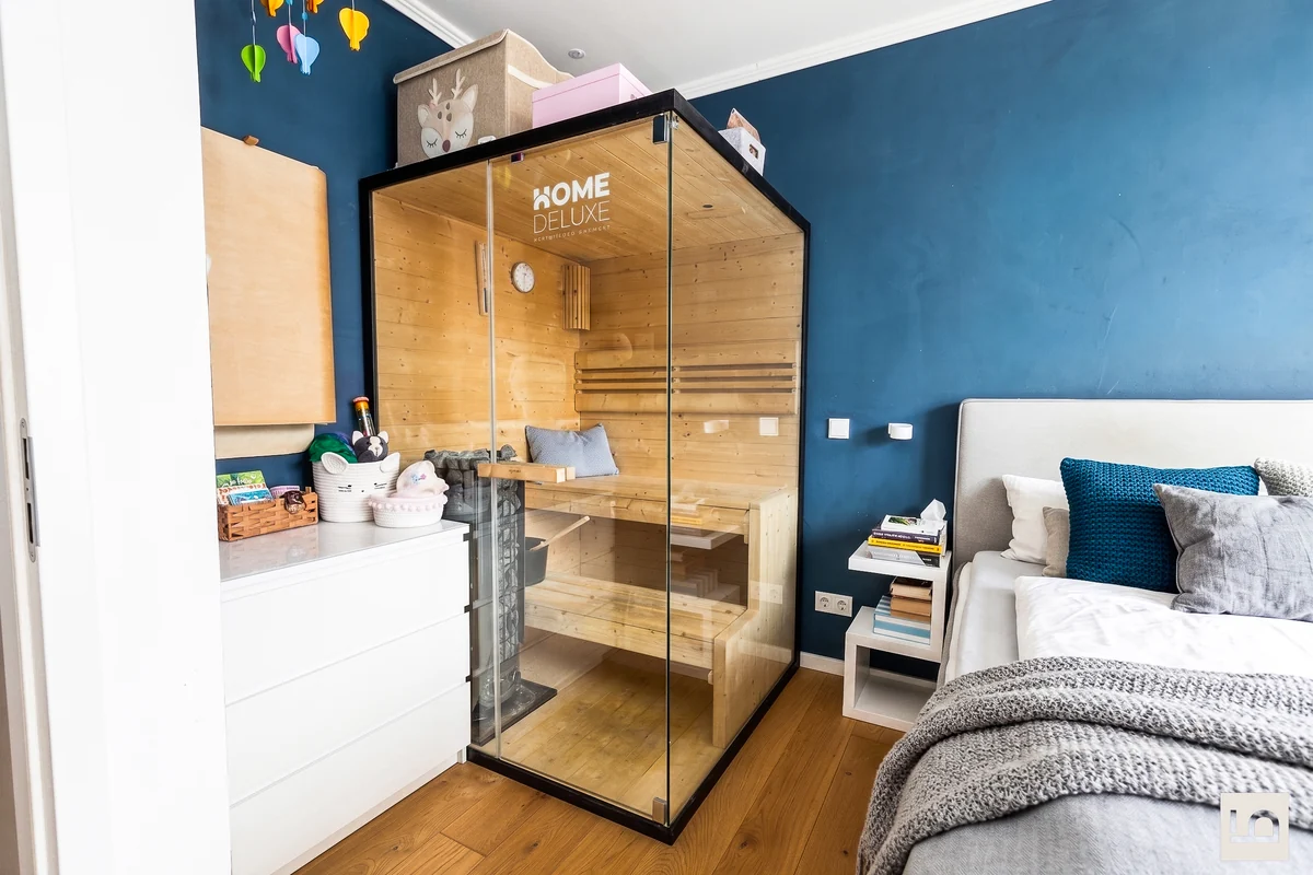 Schlafzimmer mit dunkelblauer Wand und gläserner Sauna aus Holz