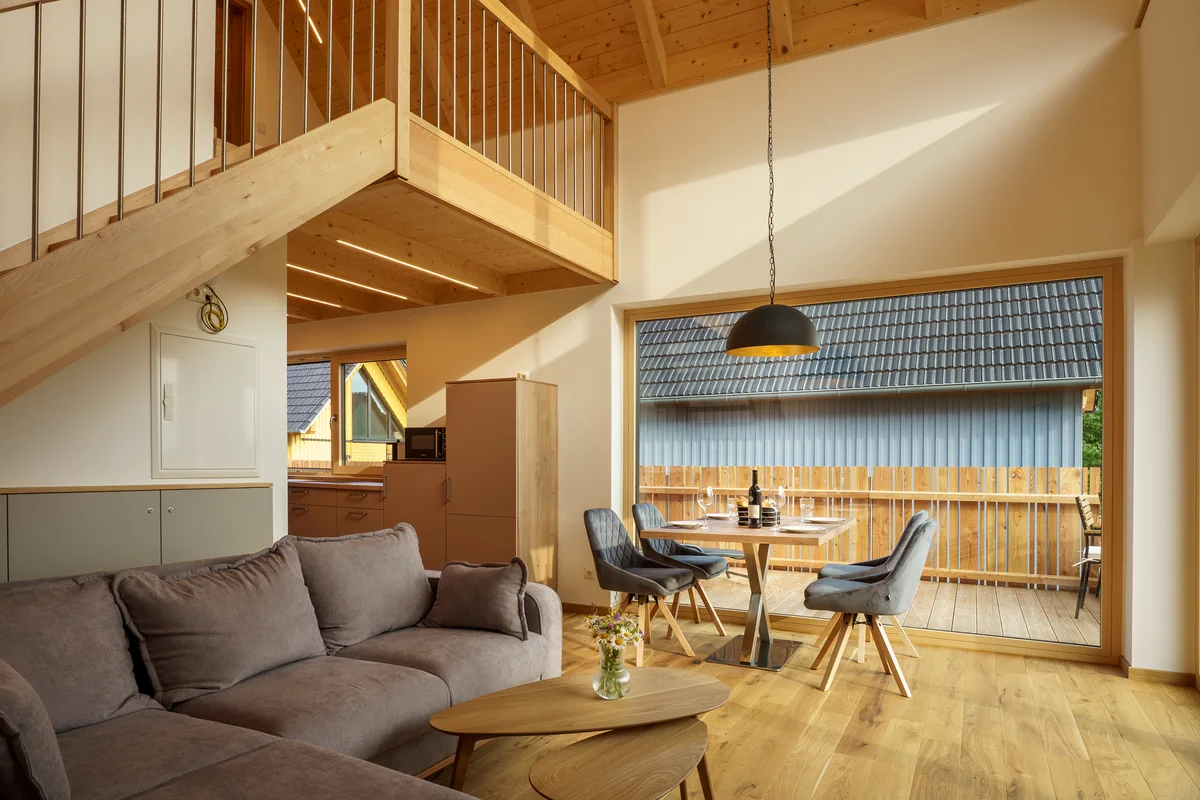 Offener Wohnbereich mit Galerie, Sofa und Essplatz in einem Holzchalet