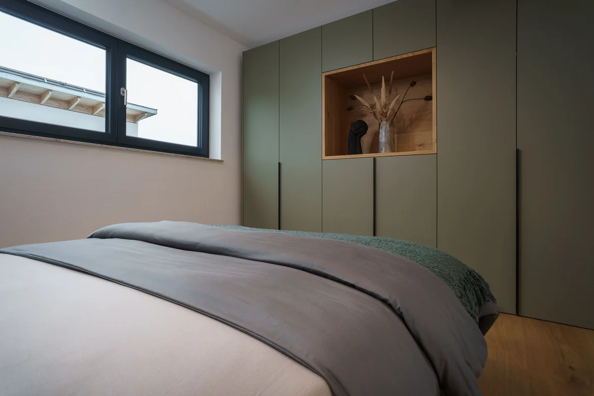 Schlafzimmer mit grauem Doppelbett und Holznische in einer Ferienwohnung