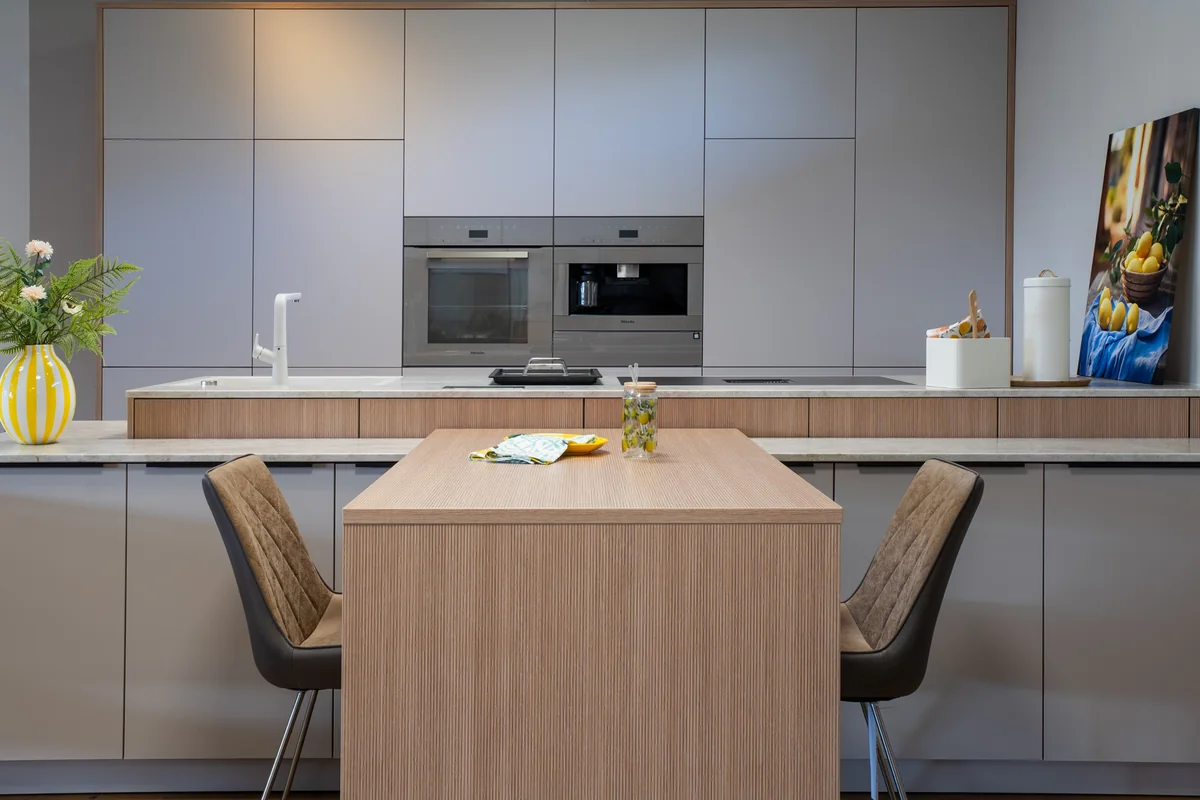 Moderne Küche mit Kochinsel und Holztisch in einer Ferienunterkunft