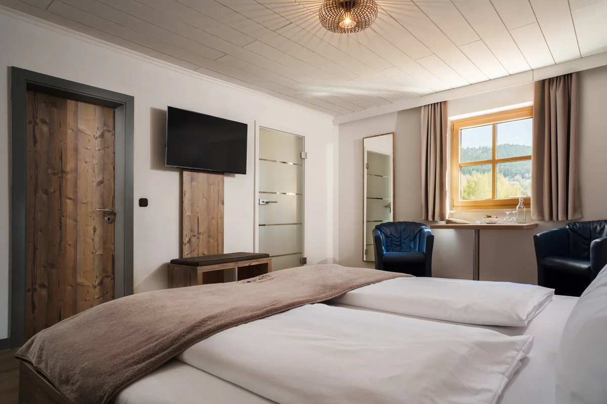 Helles Gasthofzimmer mit Holzboden, Doppelbett und Sitzecke