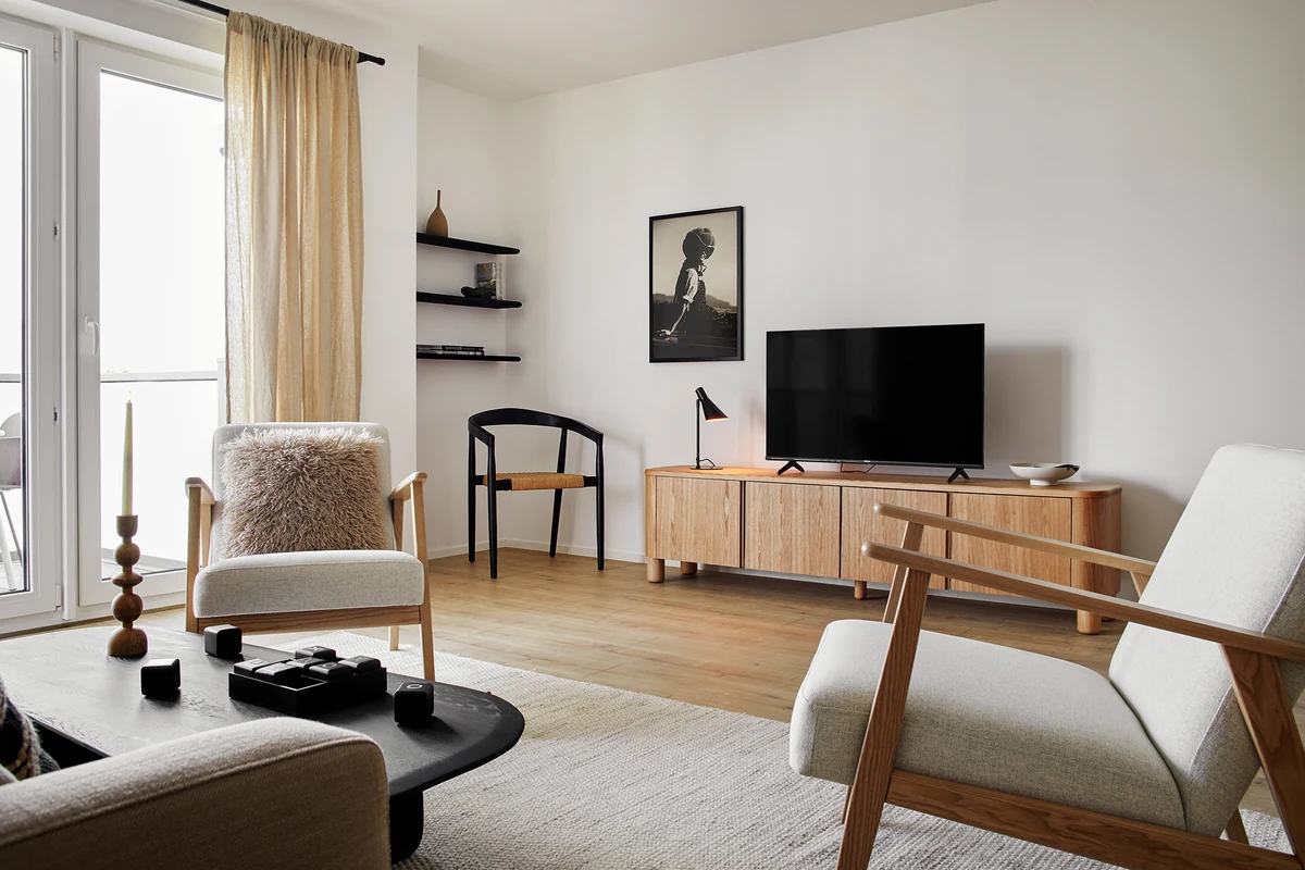 Helles Wohnzimmer einer Ferienwohnung der Matt Apartments in Offenburg mit Holzsesseln und Lowboard
