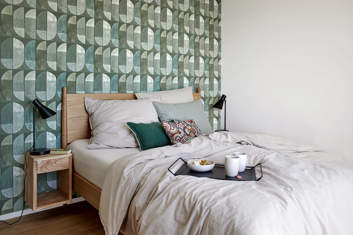 Schlafzimmer im Penthouse der Matt Apartments in Villingen-Schwenningen mit grün gemusterter Tapete hinter dem Bett