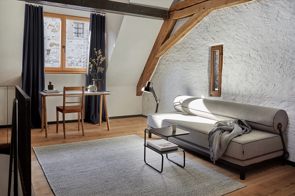 Wohnraum unter Holzbalken im Le Rossignol bei Lörrach mit Tagesbett, Schreibtisch und Teppich