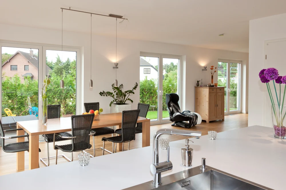 Offene Wohnküche mit Kochinsel, Esstisch und Blick in den Garten