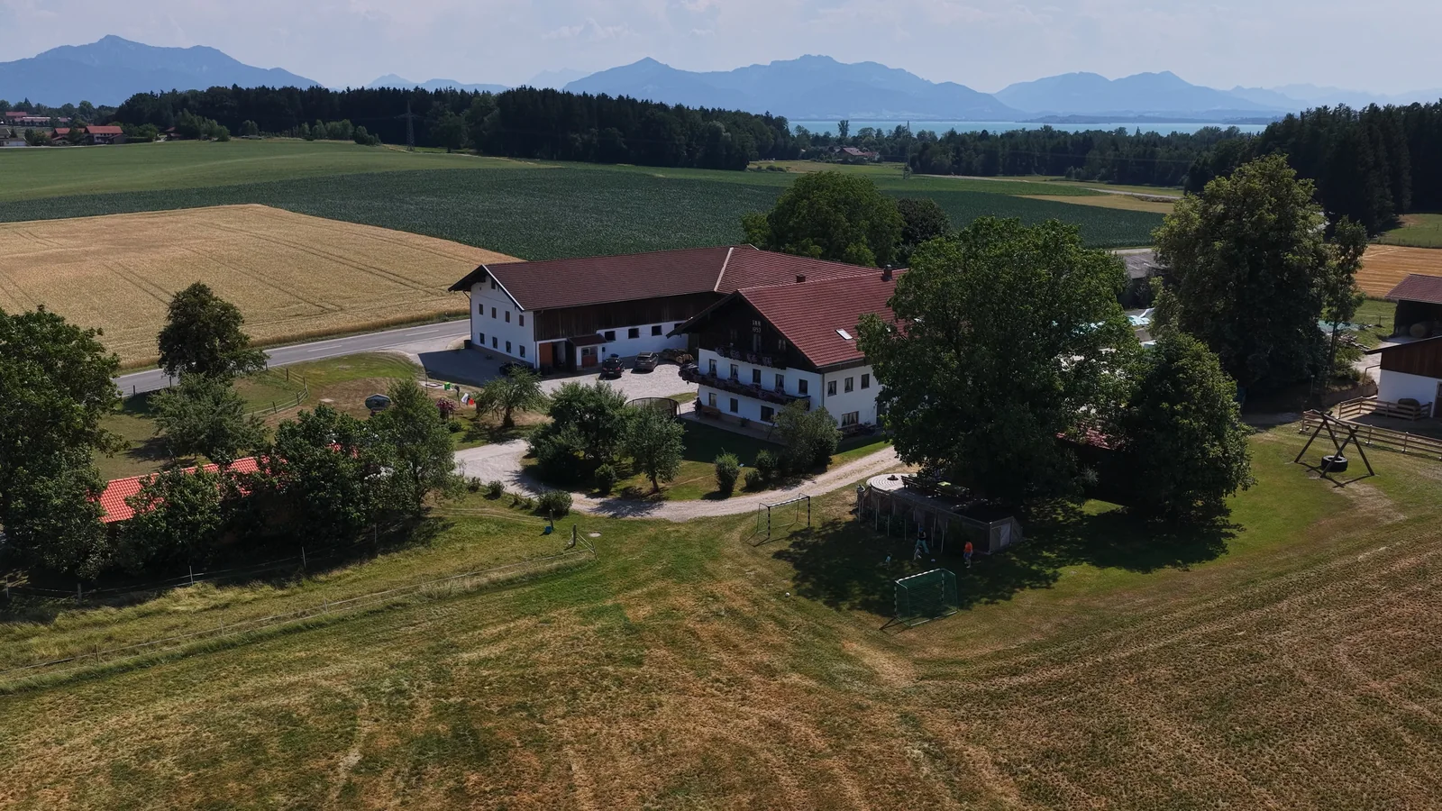 Luftaufnahme eines Ferienhofs im Chiemgau vor Alpenpanorama, fotografiert von The Landscapers