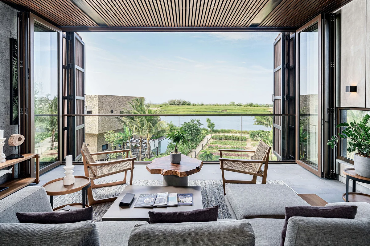 Offener Wohnraum mit Sofas, Holztisch und weitem Blick über die Terrasse ins Grüne