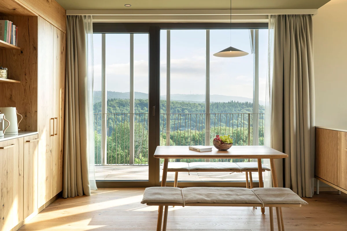 Apartment mit Holzküche, Esstisch mit Bank und Blick auf bewaldete Hügel
